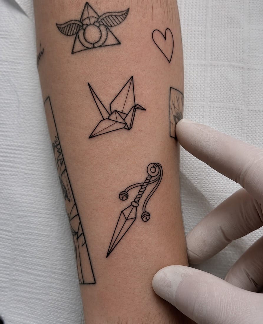 Fine line flash tattoos including an origami crane and small symbols by a London Fine Line Tattoo Academy student