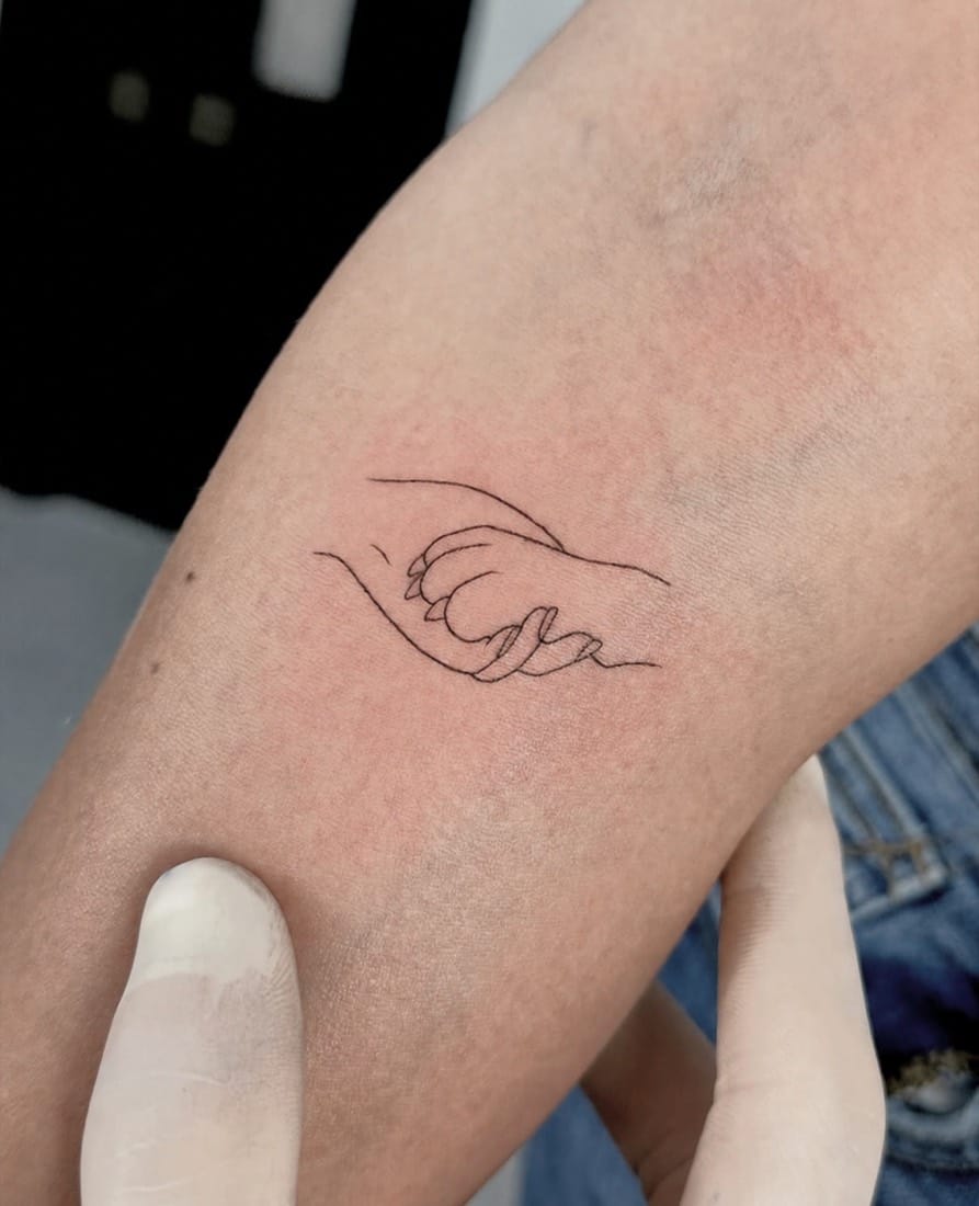 Fine line single-line tattoo of an adult and child holding hands by a London Fine Line Tattoo Academy student
